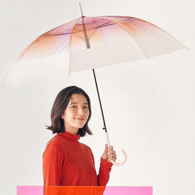 Woman holding a transparent umbrella with a pink and orange gradient on a white background